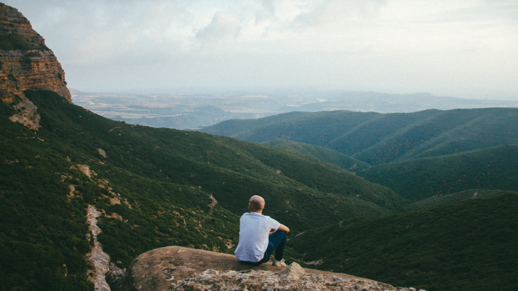 Someone sitting on a mountain overlooking green hills