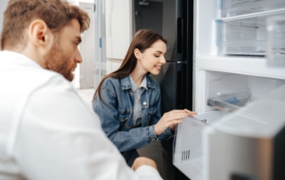 Man and woman looking at the inside design of a brand new refrigerator